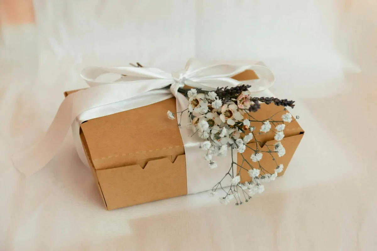 Elegante kleine Geschenkbox mit weisser Schleife und getrockneten Blumen als Taufgeschenk